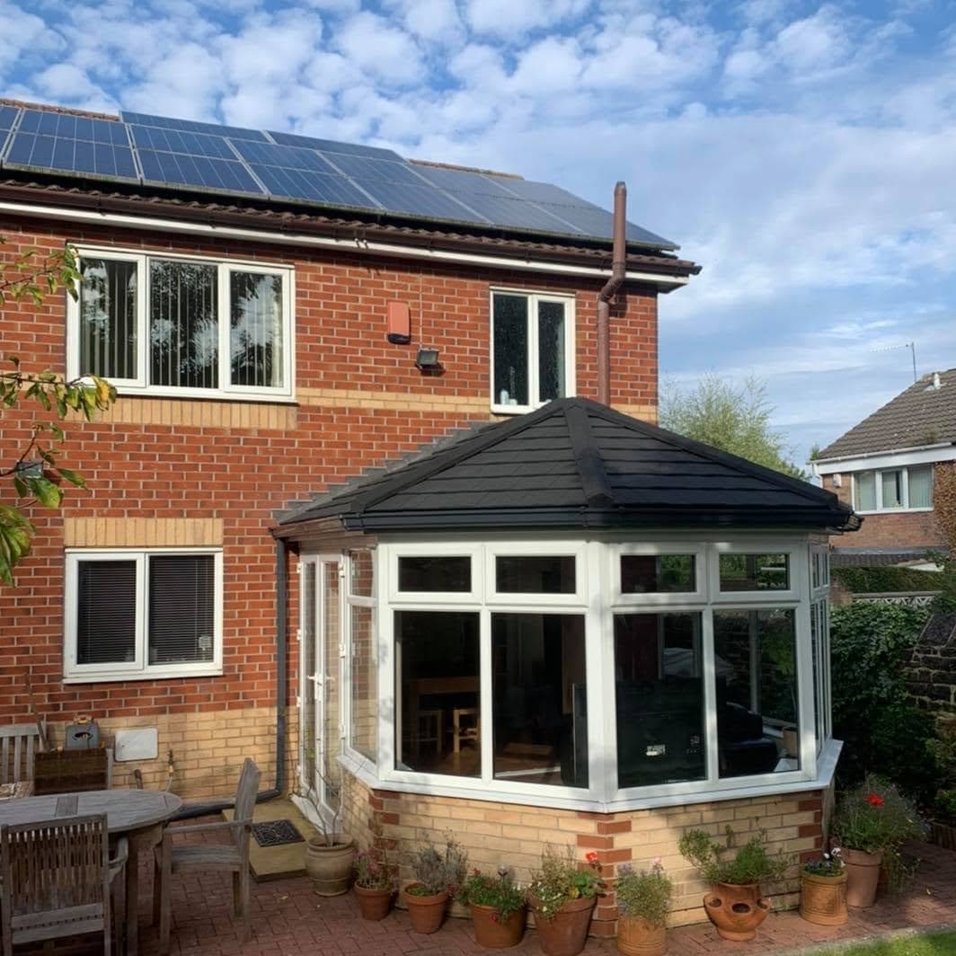 A conservatory with a solid tiled roof on a red brick house
