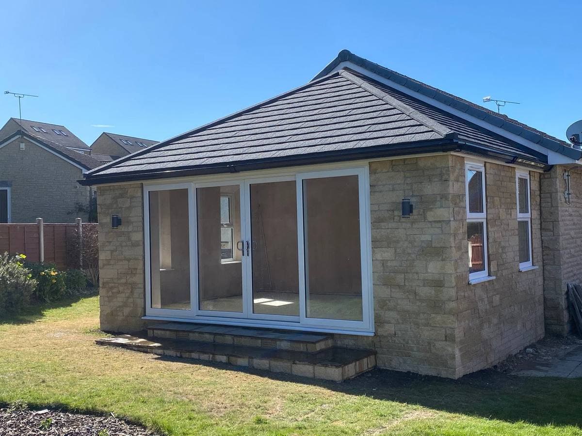 A finished stone garden room with a solid tiled roof and wide sliding doors