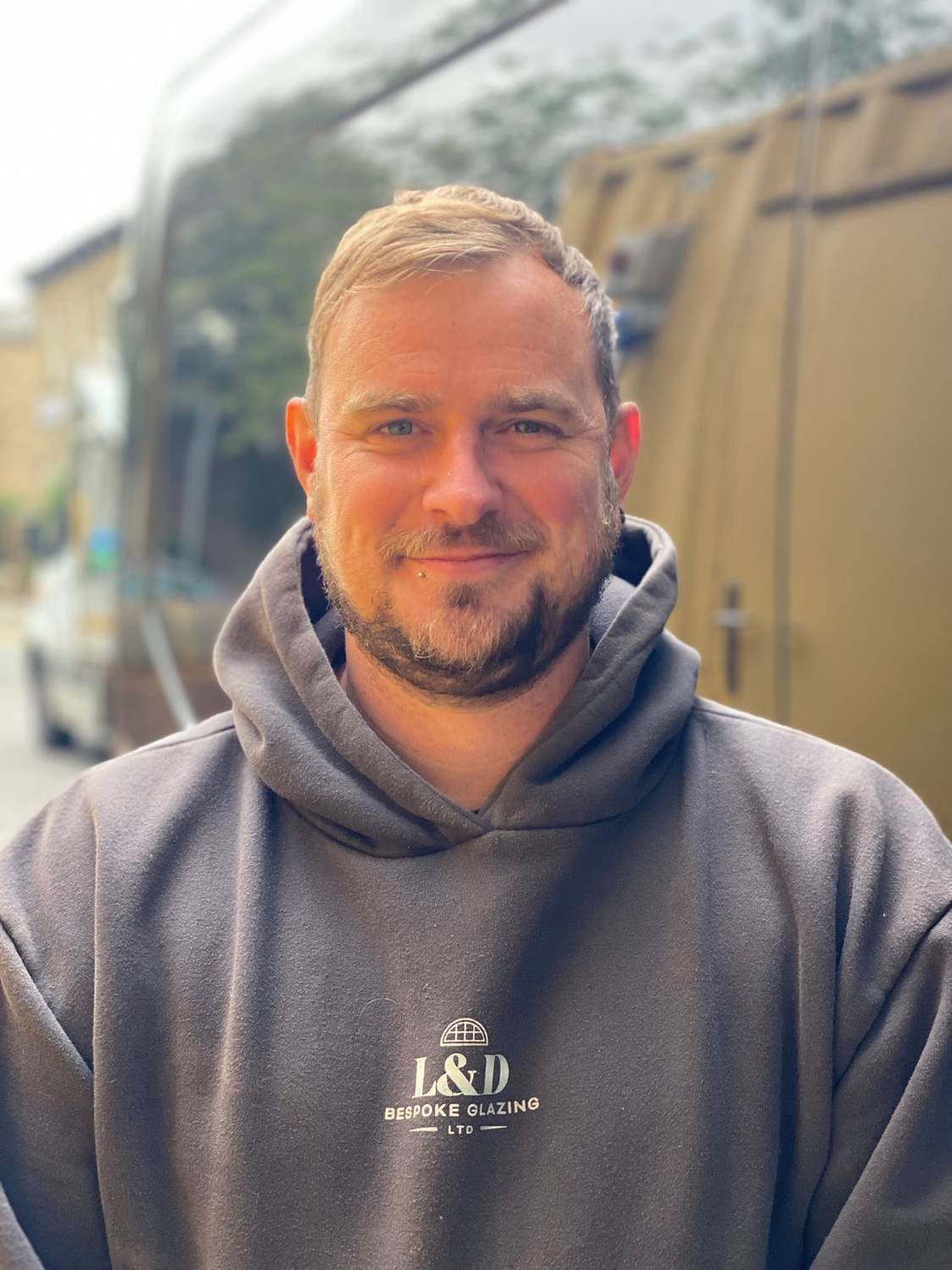 Dale Woodger of L&D Bespoke Glazing, in a company hoodie beside the works van