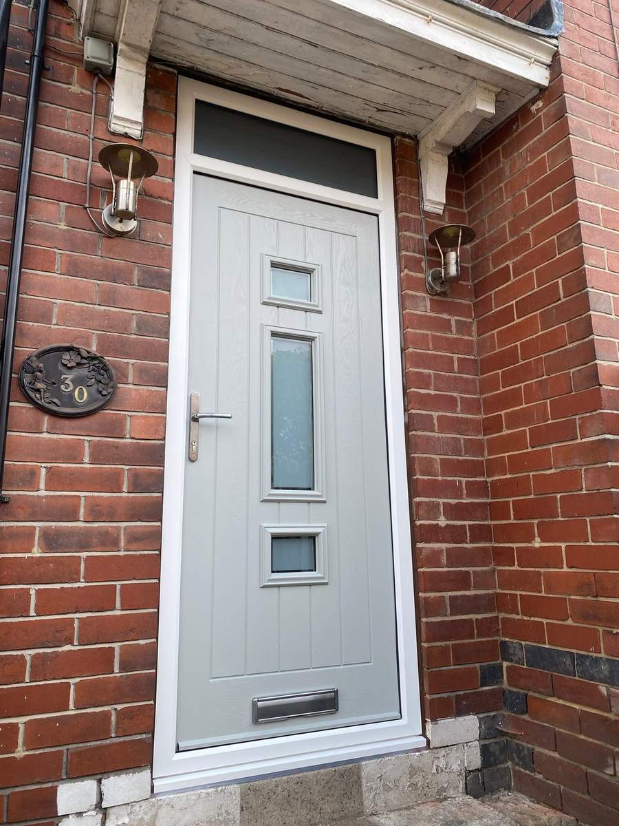 A cream composite front door with a glazed panel, in a red brick opening