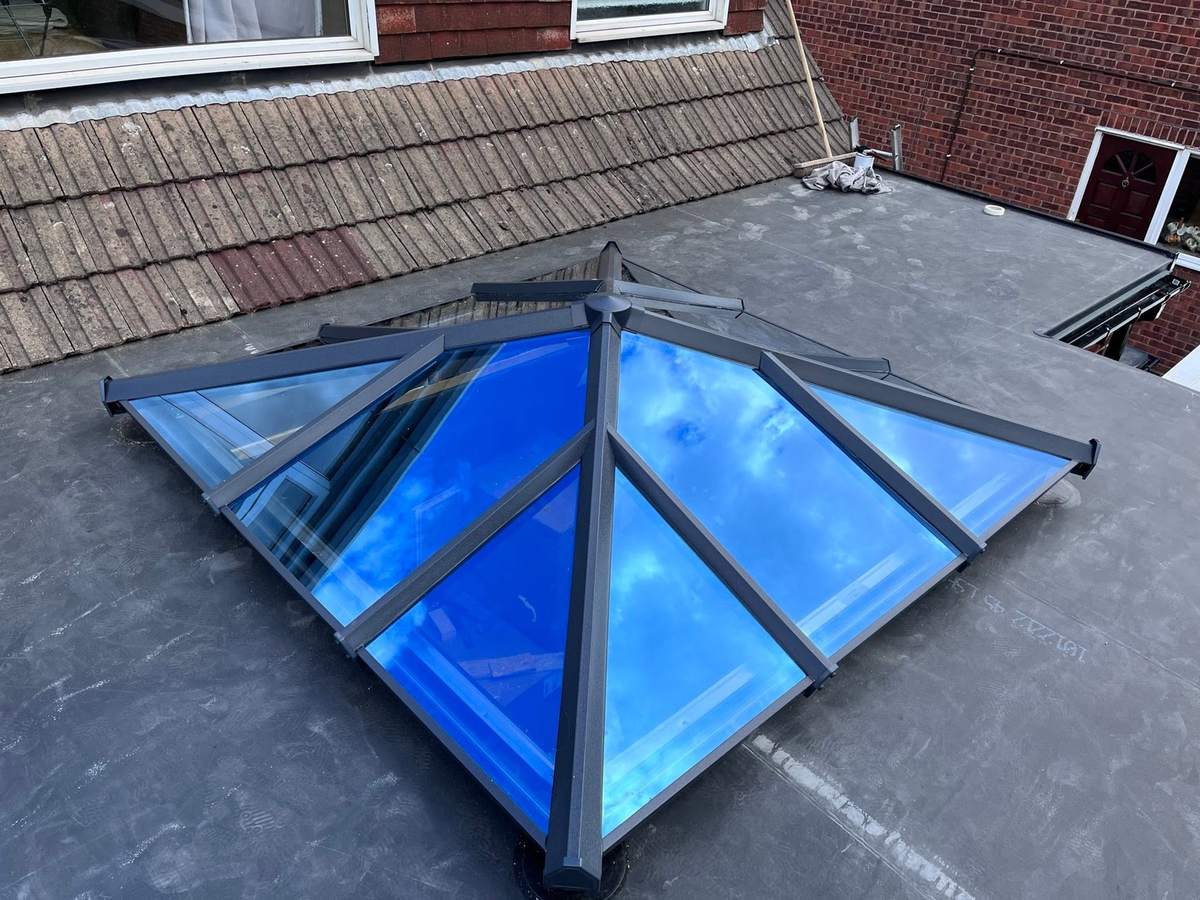 A blue glass lantern roof set into a flat roof against a clear sky